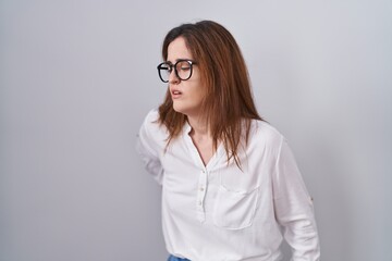 Wall Mural - Brunette woman standing over white isolated background suffering of backache, touching back with hand, muscular pain