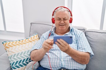 Poster - Middle age grey-haired man watching video on smartphone sitting on sofa at home