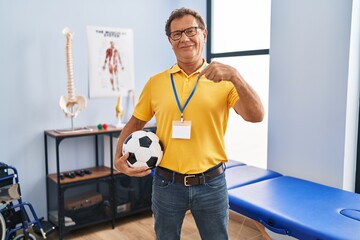 Sticker - Senior man working at sport physiotherapy clinic pointing finger to one self smiling happy and proud