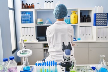 Brunette woman working at scientist laboratory standing backwards looking away with crossed arms