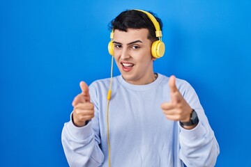 Poster - Non binary person listening to music using headphones pointing fingers to camera with happy and funny face. good energy and vibes.