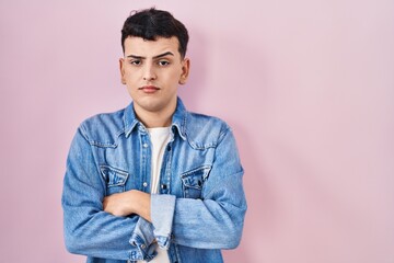 Sticker - Non binary person standing over pink background skeptic and nervous, disapproving expression on face with crossed arms. negative person.