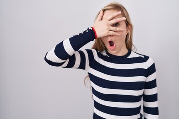 Canvas Print - Young caucasian woman wearing casual navy sweater peeking in shock covering face and eyes with hand, looking through fingers with embarrassed expression.