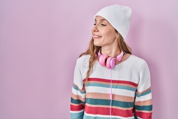 Poster - Young blonde woman standing over pink background looking away to side with smile on face, natural expression. laughing confident.