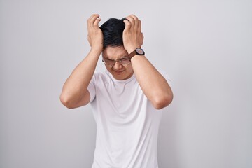 Sticker - Young asian man standing over white background suffering from headache desperate and stressed because pain and migraine. hands on head.