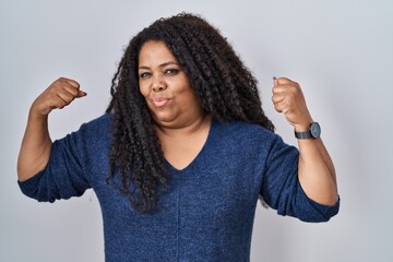 Poster - Plus size hispanic woman standing over white background showing arms muscles smiling proud. fitness concept.