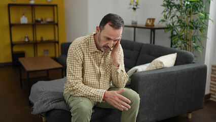 Sticker - Middle age man sitting on sofa with serious expression at home