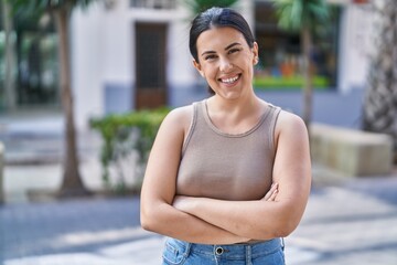 Wall Mural - Young beautiful hispanic woman standing with arms crossed gesture at street