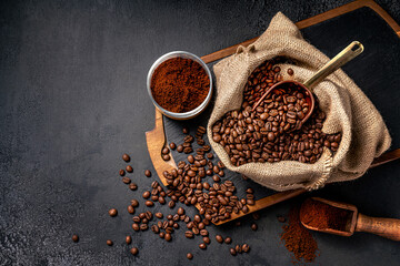 Wall Mural - Scoop of coffee beans in a bag on dark board. Top view of ground coffee in a cup and instant coffee in a wooden cup. Place for text.