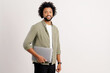 © Vadim Pastuh - Attractive 30s African American man wearing green casual shirt standing isolated on white, carrying laptop computer, smiling, male office employee, student, copy space