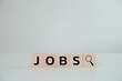 Job search concept. People searching for a new job, find your career. Wooden cube block with jobs lettering and magnifying glass icon on white background.