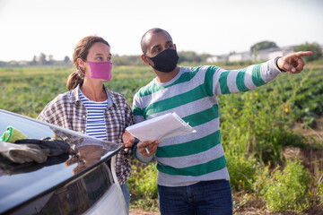 Wall Mural - Courier in protective mask invites the farmer to sign documents on the farmer field