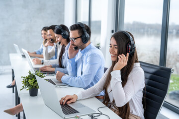 Wall Mural - Group of call center workers with headsets using laptops in office.