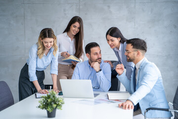 Business team people discussing project and communicating while sitting and standing around office desk.