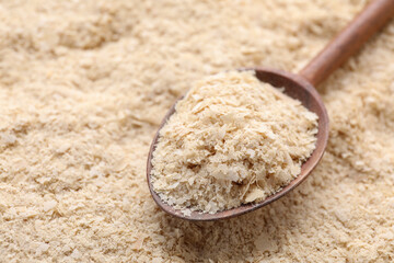 Wooden spoon of brewer`s yeast on flakes, closeup. Space for text