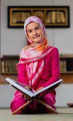 Wall Mural - A happy Muslim girl reading a holy book Quran inside the mosque. 