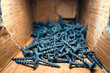 Small black wood screws close-up in a cardboard box