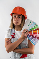 Wall Mural - girl builder stands in a hard hat with color samples in hands for choosing color of the wall.