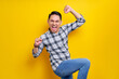 © Bangun Stock Photo - Excited young handsome Asian man celebrating success with raised fists isolated on yellow background. People lifestyle concept