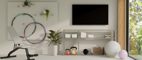 Modern home fitness room interior design with TV screen on white wall, sport bench, yoga ball