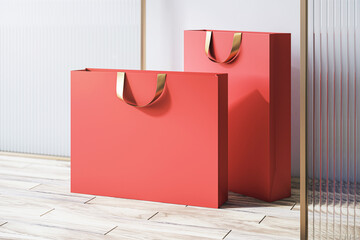Poster - Perspective view on blank red paper shopping bags with space for your brand name or text on wooden floor near decorative partition and light wall background, closeup. 3D rendering, mock up