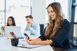 © Westend61 - Smiling businesswoman using mobile phone at desk in office