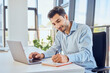 © Westend61 - Businessman taking down notes in diary by laptop at office