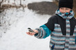 © Cavan Images - Young boy hand feeding a chickadee bird on a snowy winter day.
