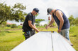 © Cavan Images - Two men preparing steel excursion for solar panel installation.