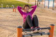 © Westend61 - Happy mature woman with hands behind head doing sit-ups in park
