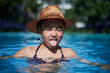 © Cavan Images - Cute young mixed race girl wearing a straw hat posing inside the pool