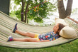 © Cavan Images - A little girl lays on a hammock by self in sunshine with closed eyes