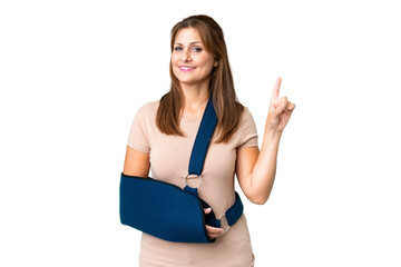 Canvas Print - Middle age with broken arm and wearing a sling over isolated background showing and lifting a finger in sign of the best