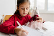 © Westend61 - Girl with unicorn toy studying at home