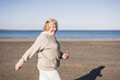© Westend61 - Smiling senior woman walking by sea at beach