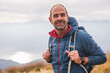 © Westend61 - Smiling mature man with backpack standing under sky