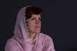 Nice portrait of beautiful mature Caucasian woman wearing cream-colored shawl against dark background