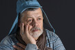 Indoor portrait of sad Ukrainian senior man in blue shirt and kids cap