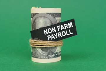 On a green surface, rolled dollars with a black sign that says - NON FARM PAYROLL