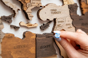 Wall Mural - Close up woman pushes pin with Israel flag into wooden map. Visited the country on the vacation concept 