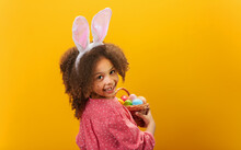 A Black Girl With Rabbit Ears On Her Head With A Basket Full Of Colored Eggs.