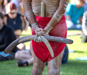 Australian Aboriginal culture, a man is holding boomerangs behind his back, the ritual rite at the community event, symbol of indigenous culture and traditions