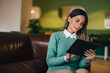 © bnenin - Smiling businesswoman using a digital tablet, sitting on the couch.