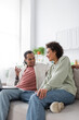 © LIGHTFIELD STUDIOS - African american couple talking near laptop on couch at home.