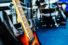 A Fragment Of An Electric Guitar Against The Backdrop Of A Concert Venue. Preparation For A Musical Performance Or Rehearsal Of A Musical Group. Foreground