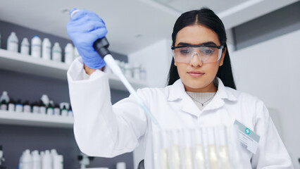 Poster - Female scientist experimenting with test tubes and a syringe. One young biologist or chemist putting blue liquid in glassware for medicinal research testing at an innovative research lab or clinic