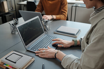 Fototapete - Close-up of young female broker with laptop analyzing financial data and drawing graph illustrating development of stock market