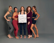 © gpointstudio - Five women in sports clothes in studio shot holding a banner