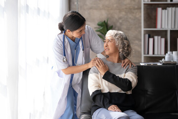 Asian female doctor or nurse gently guide and care for elderly patient at home, giving warm encouragement and consolation.