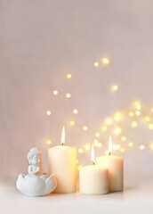 Wall Mural - little Buddha statue and burning candles on table close up, abstract blurred light background. esoteric spiritual practice, Relax time, harmony, meditation. life balance concept